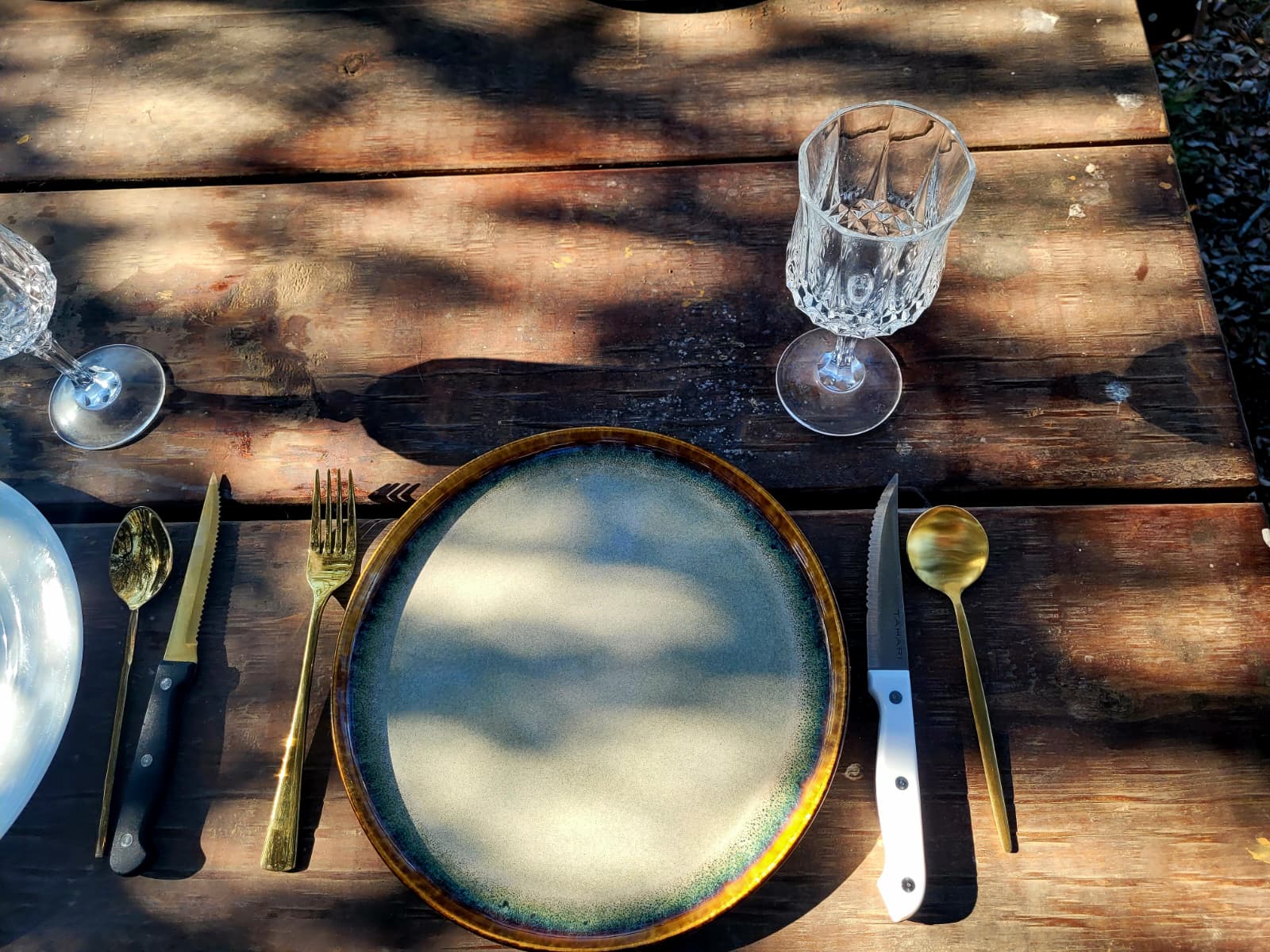 A place setting with gold cutlery and crystal glass on the long table