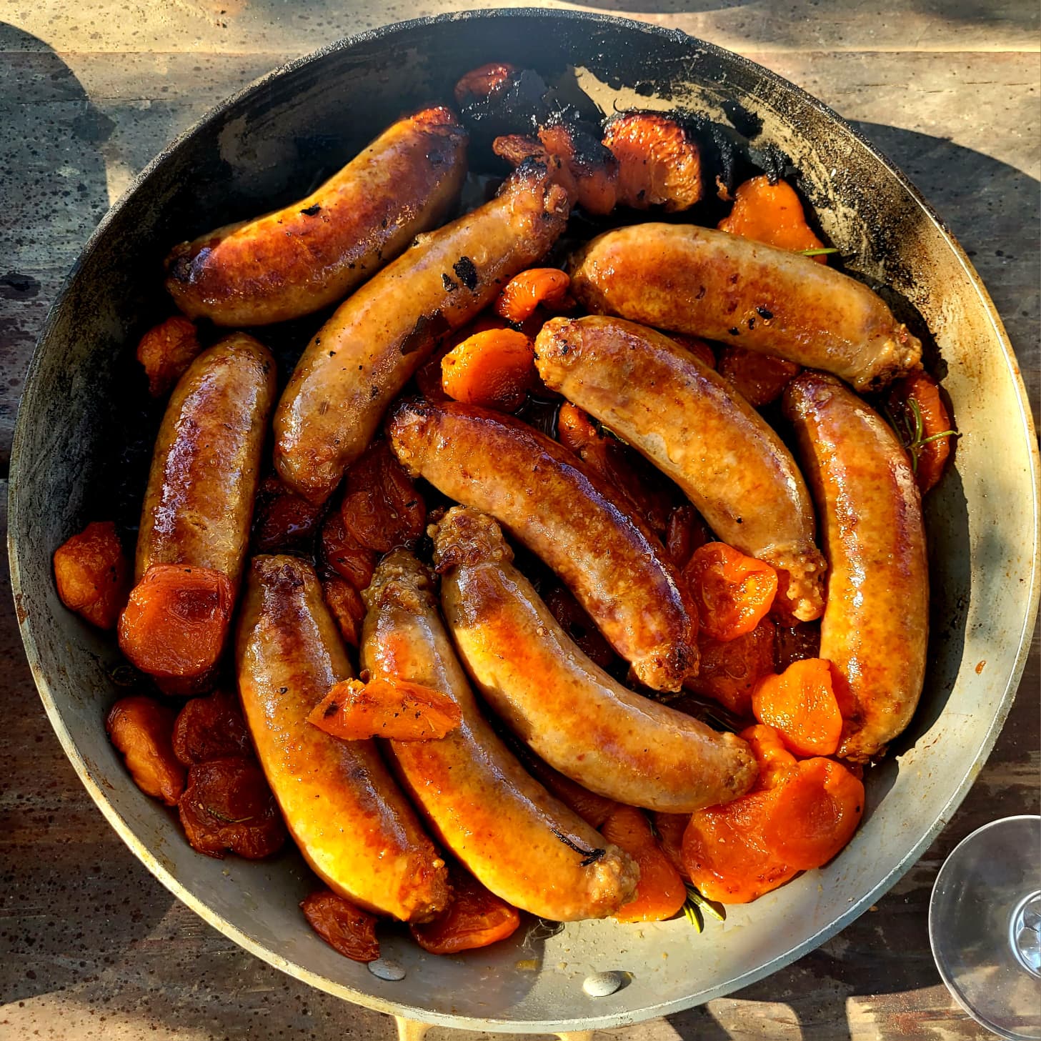 Sausages roasted with apricots and rosemary in a pan