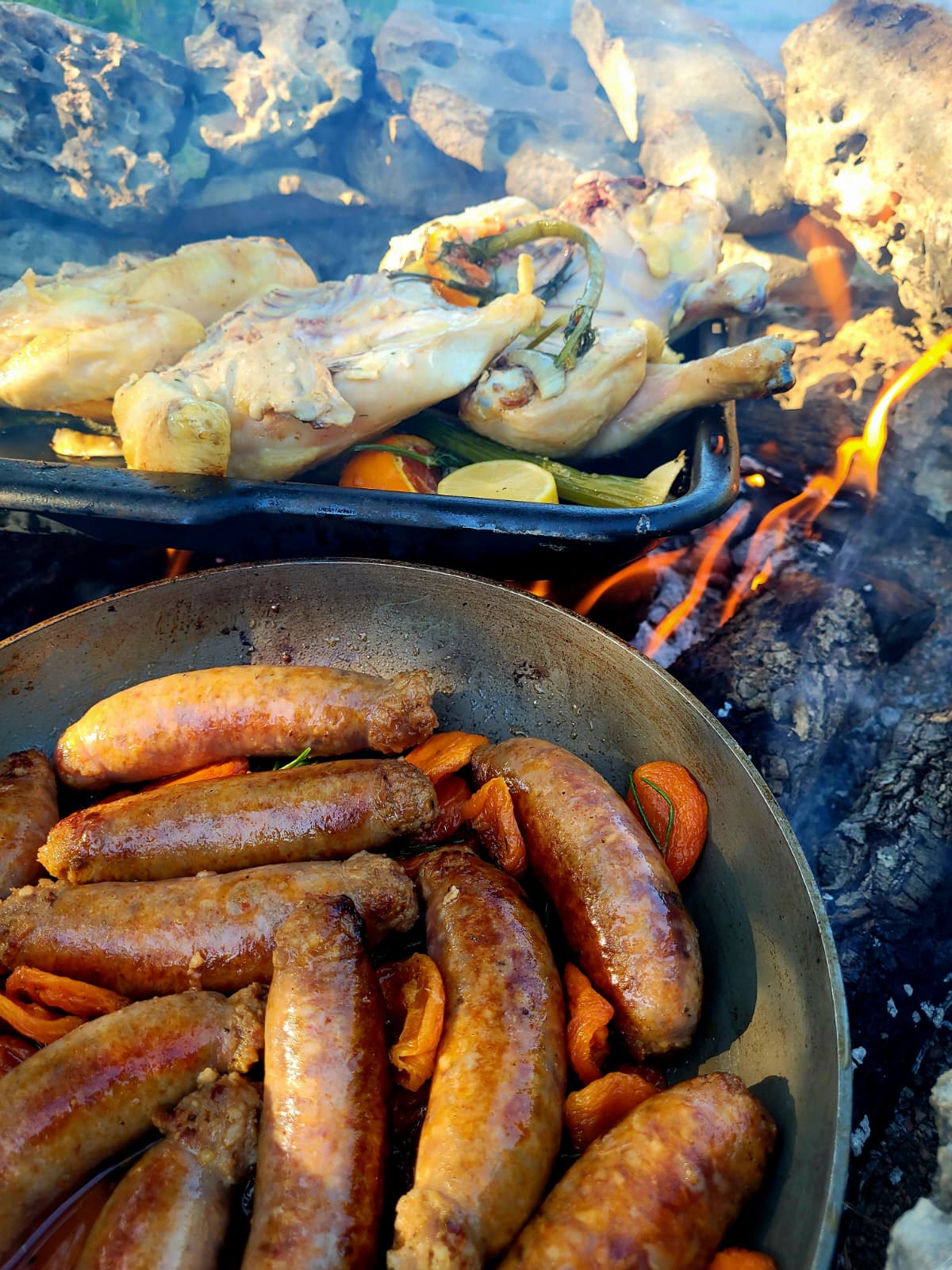 Sizzling sausages with apricots in a pan over the fire