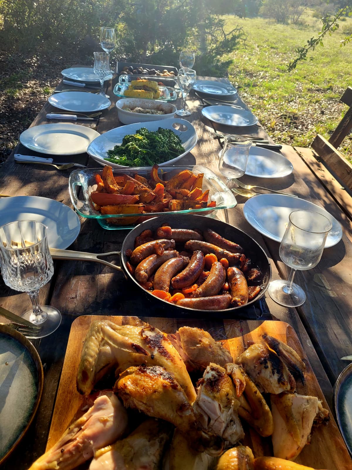 Roast squash, greens, sausages and carved chicken down a long outdoor table